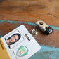 A detailed view of the Clothing Protector ID Strap Clip with Rubber Tip, 2105-3170, featuring an ID badge with a photo, all placed on a wooden surface.