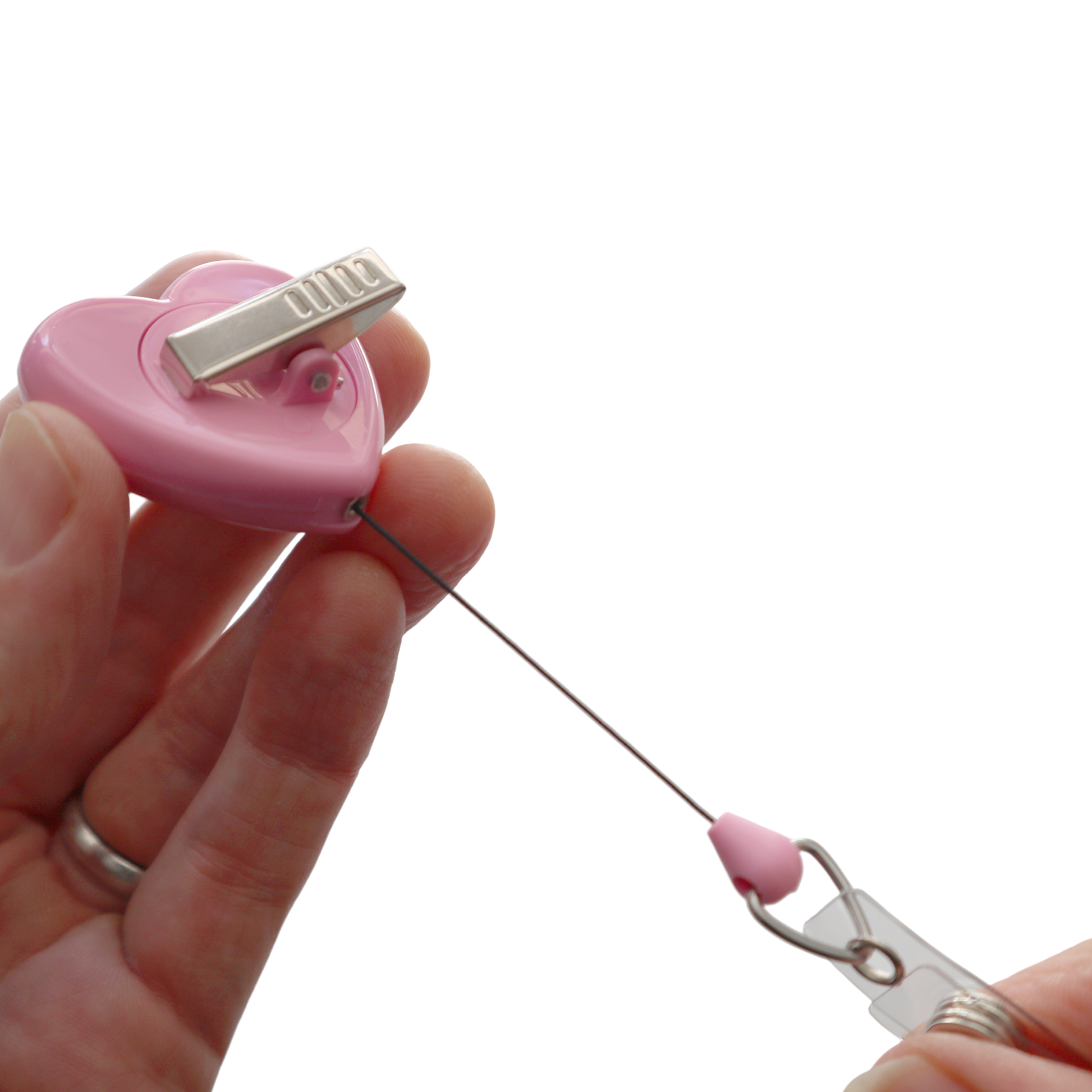 A person holding the Heart Shaped Ribbon "Awareness" Badge Reel with a pink hue, featuring a retractable design and equipped with a metal swivel spring clip.