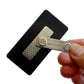 A hand holding a Magnetic ID Badge Holder Sticky Back (P/N 5730-3000) next to a black card with a metal plate attached to it.