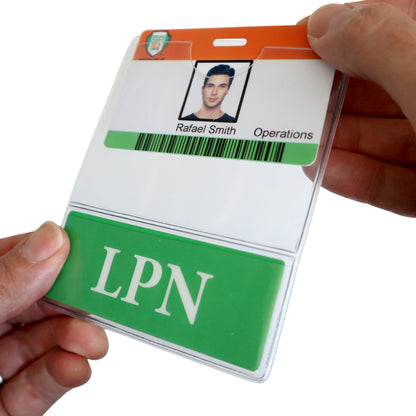 A person holds an ID badge with a photo. The name "Rafael Smith" and the title "Operations" are visible, along with a green section labeled "LPN". The badge is housed in an LPN BadgeBottom Badge Holder & LPN Badge Buddy IN ONE!! - Horizontal ID Badge Sleeve with Bottom Role Tag for Nurses, ensuring it remains intact and professional.