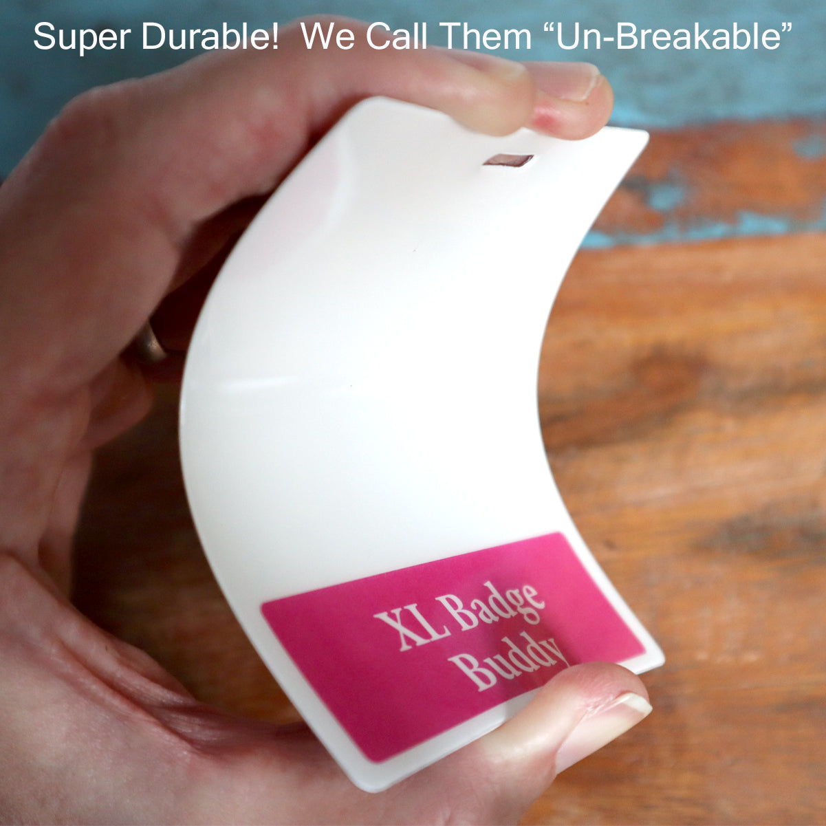 Close-up of a hand bending a white plastic badge labeled "Oversized STUDENT NURSE Badge Buddy - XL Badge Backer for Student Nurses - Horizontal Hospital ID Badge Buddies," demonstrating its durable design with the text "Super Durable! We Call Them 'Un-Breakable'" above.