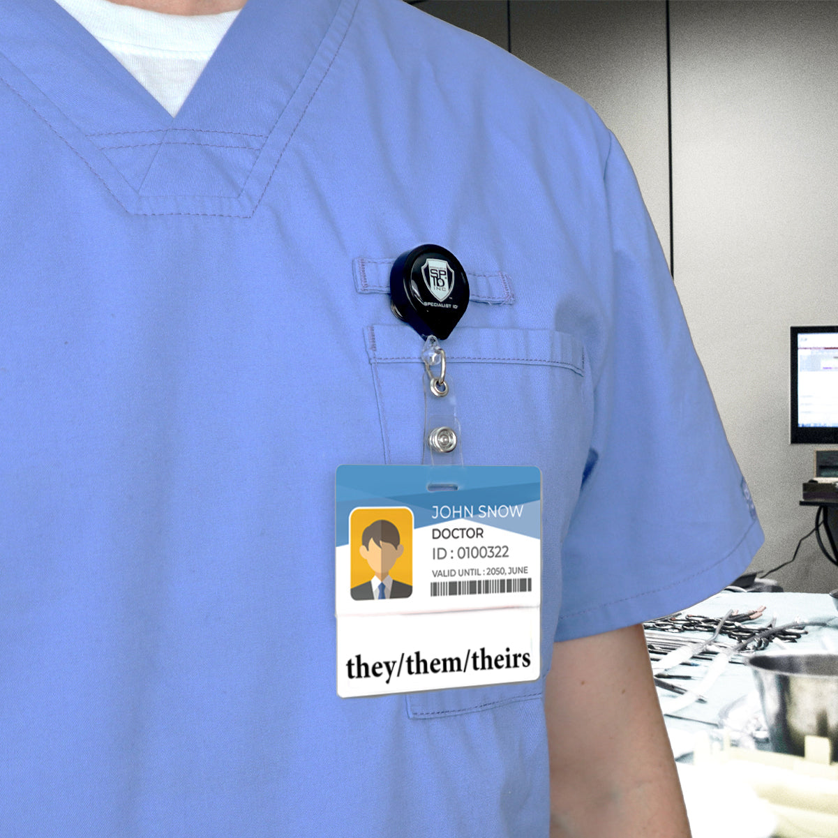 A person in blue scrubs has a "Doctor" badge with a cartoon avatar and the Pronouns Badge Buddy They/Them/Theirs Gender Neutral - Horizontal with White Border, emphasizing inclusivity among healthcare professionals.