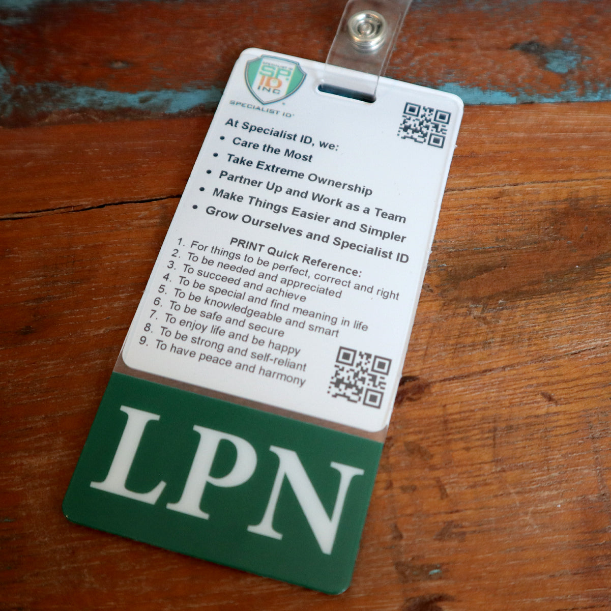 Photo of a vertical ID badge, labeled "LPN" at the bottom. The Clear LPN Badge Buddy Vertical with Green Border for Licensed Practical Nurses lists company values and provides a quick reference guide for success, highlighting teamwork, ownership, and personal growth for Licensed Practical Nurses.