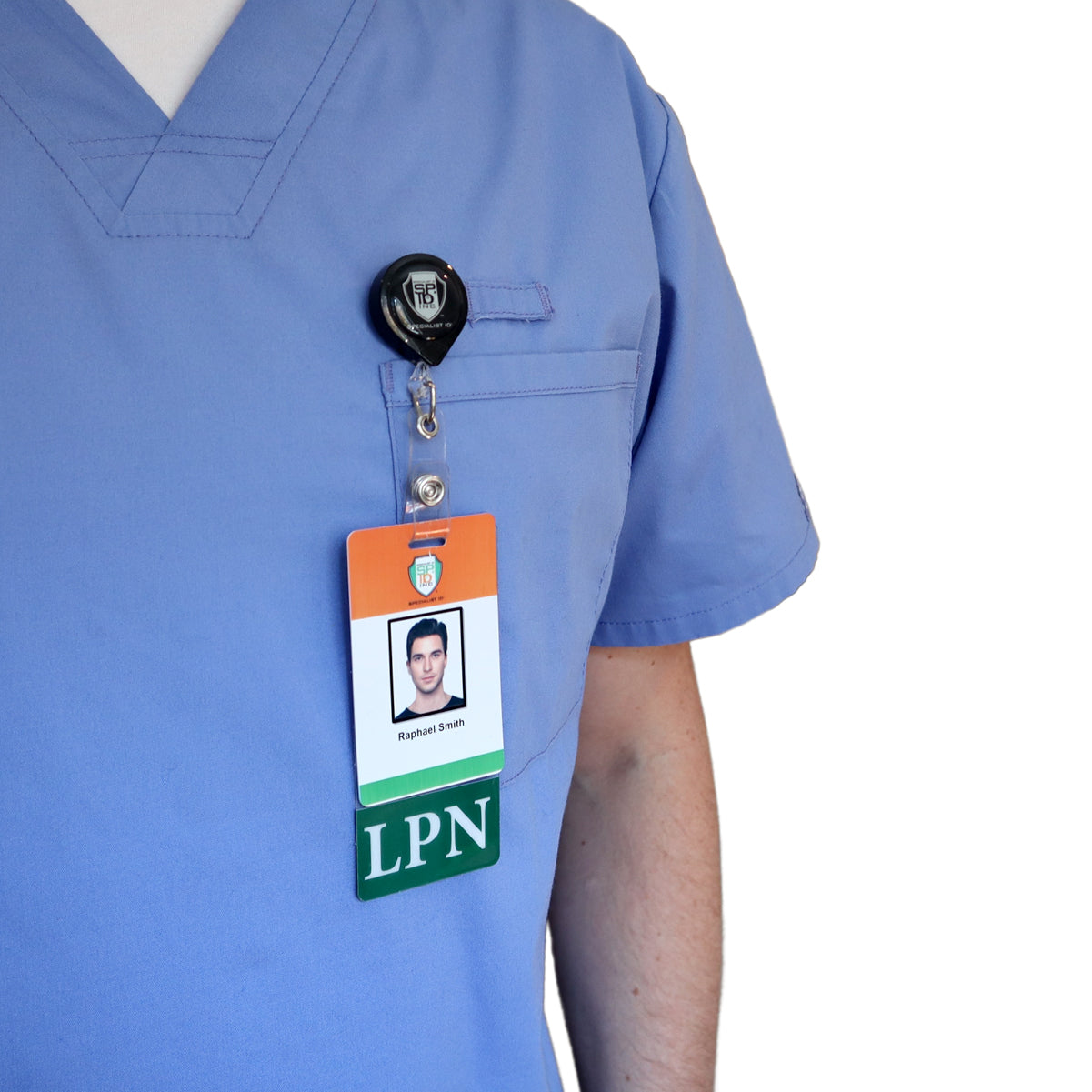A person wearing a light blue medical scrub top with a Clear LPN Badge Buddy Vertical with Green Border for Licensed Practical Nurses and a vertical ID badge displaying a photo, the name Raphael Smith, and "LPN" text attached.