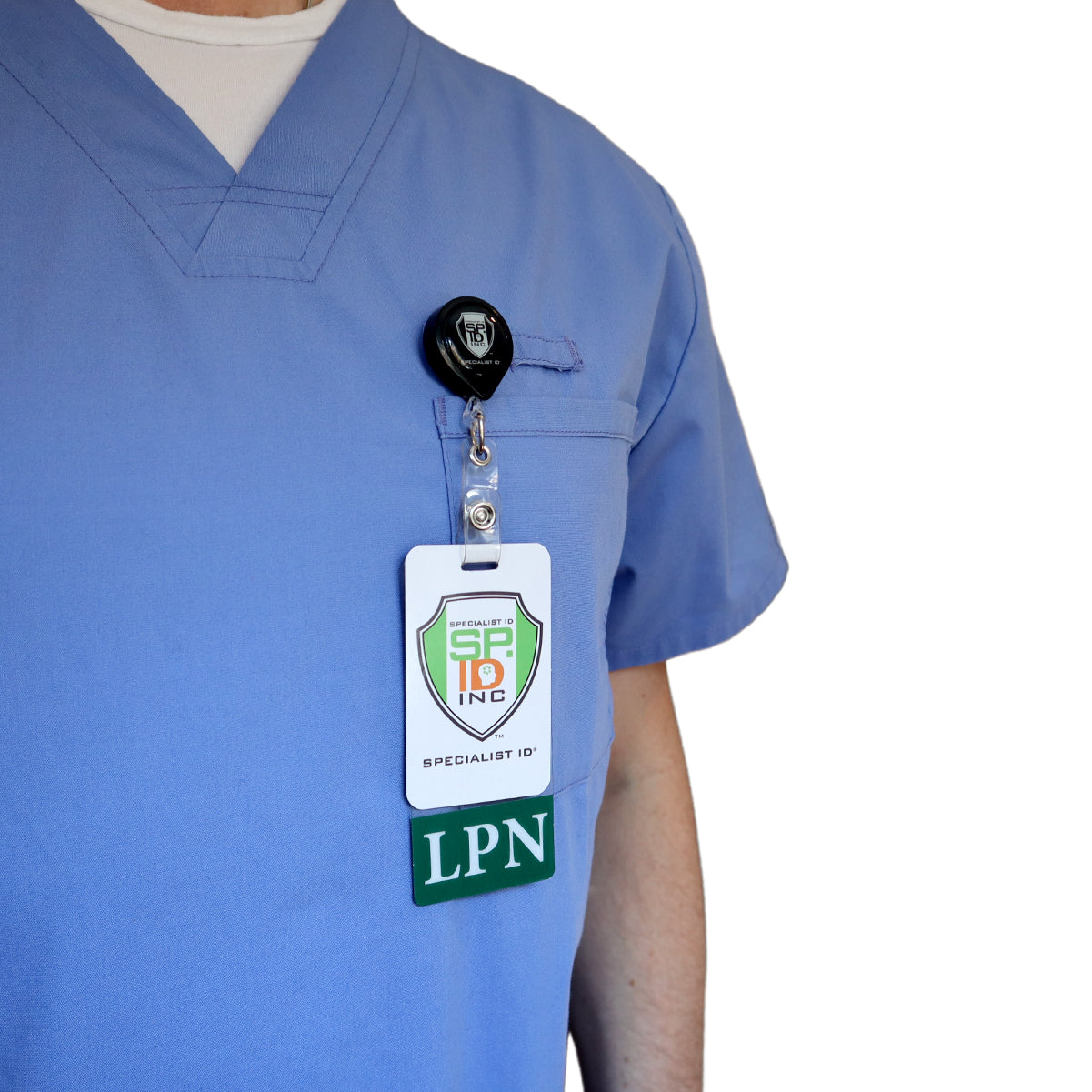 A person is wearing a blue medical scrub top with a Clear LPN Badge Buddy Vertical with Green Border for Licensed Practical Nurses clipped to the chest pocket that reads "LPN.