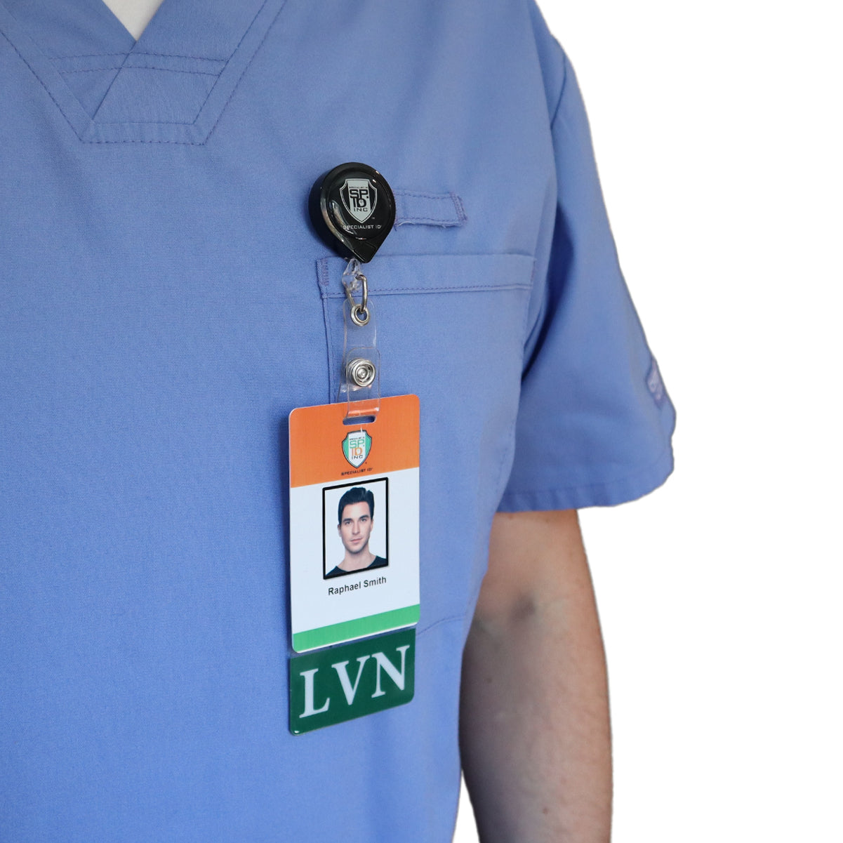 Person wearing light blue scrubs with a retractable badge holder clipped to their pocket. The vertical ID badge features a Clear LVN Badge Buddy Vertical with Green Border for Licensed Vocational Nurses, showcasing the photo ID with the name 'Raphael Smith' and the designation 'LVN', emphasizing his status as one of the licensed vocational nurses.