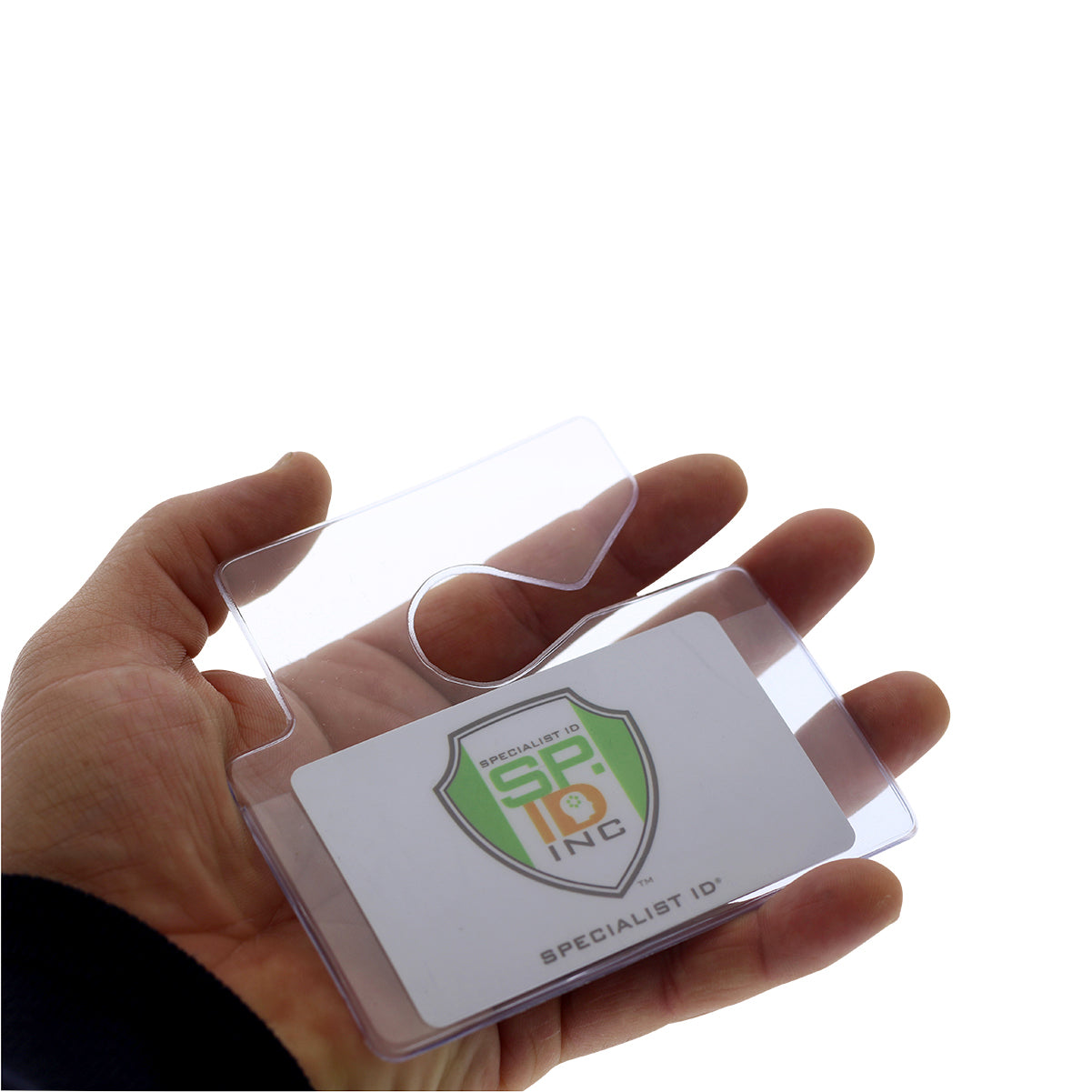 A hand holds a Clear Rigid Vinyl Horizontal Parking Pass Vehicle Hang Tag Holder, containing a white and green card with the text "SP INC" and "SPECIALIST ID.