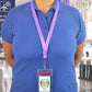 Person in a blue polo shirt with a purple lanyard and an ID badge in a Heavy Duty Vertical Multi-Card Badge Holder with Resealable Zip Top (1815-1110), standing in a bright, spacious indoor setting. The resealable top of the vertical ID display reveals the "Specialist 10" logo with text below it.