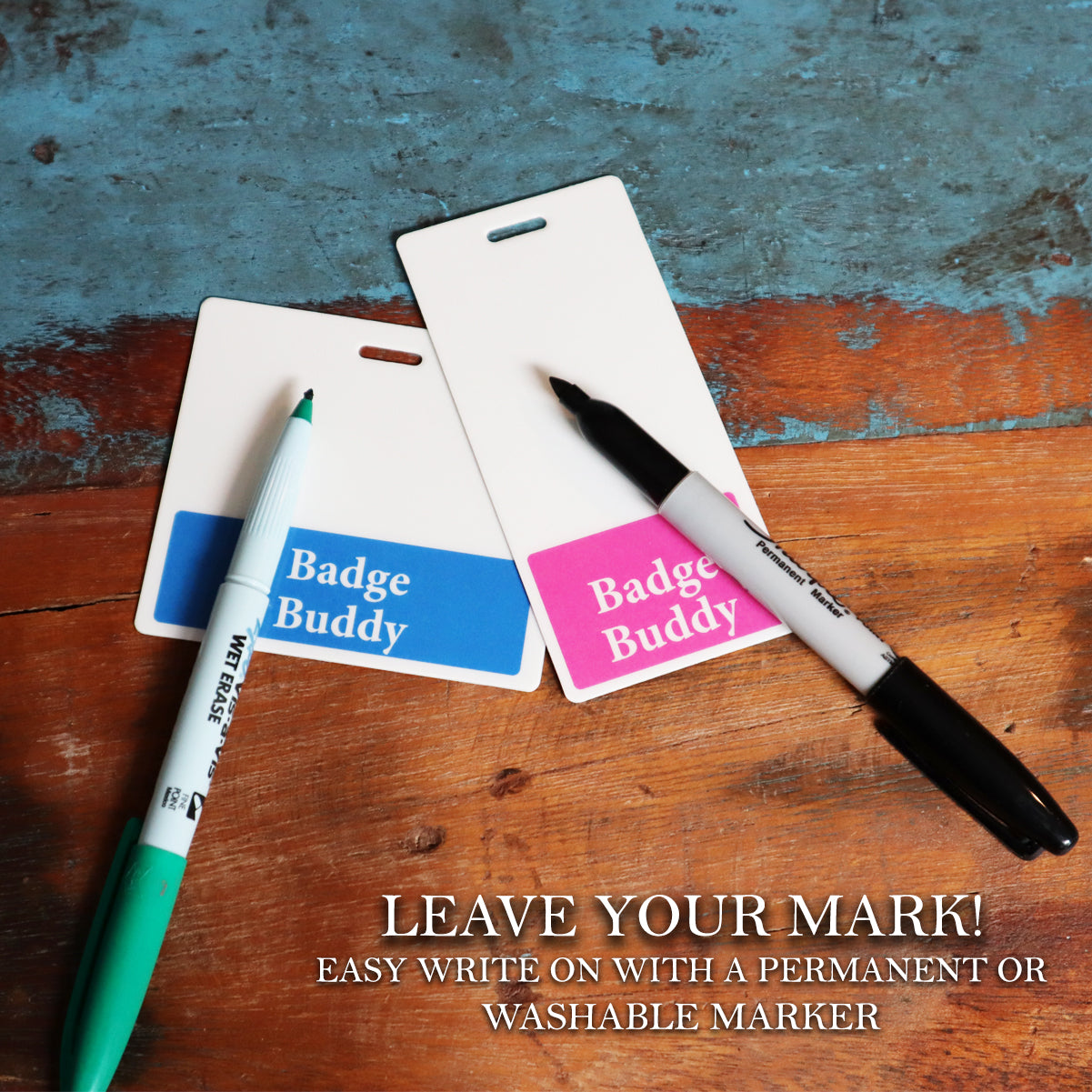 Two Pronouns Badge Buddy They/Them/Theirs holders rest on wood with a green and black marker. The text reads: "Leave your mark! Easy write on with permanent or washable marker." Perfect for expressing gender-neutral pronouns and promoting diversity, equity, and inclusion.