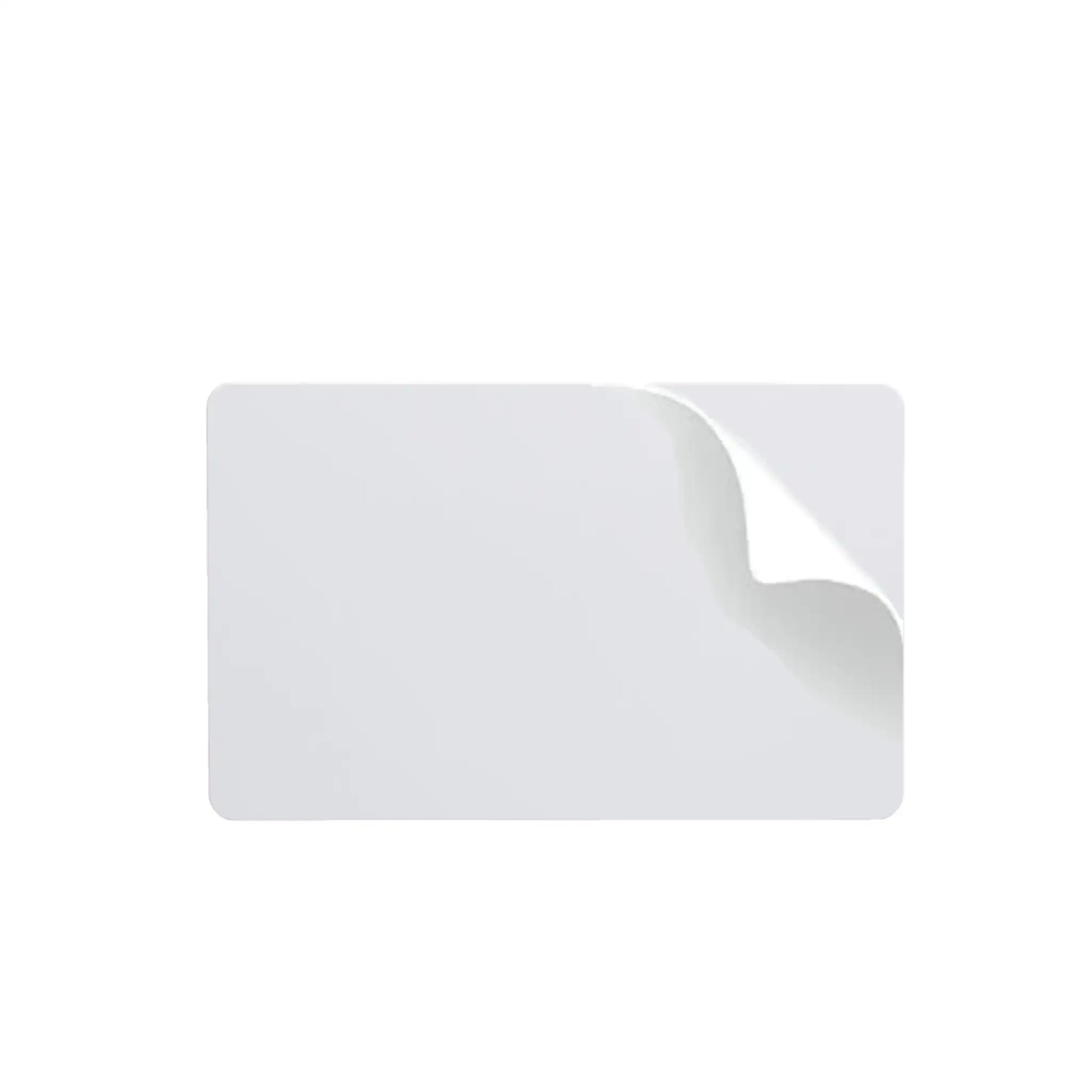 A rectangular white Fargo 81759 UltraCard 10 mil PVC card with a peeled corner that reveals a subtle curl and its adhesive backing. The background is plain white.