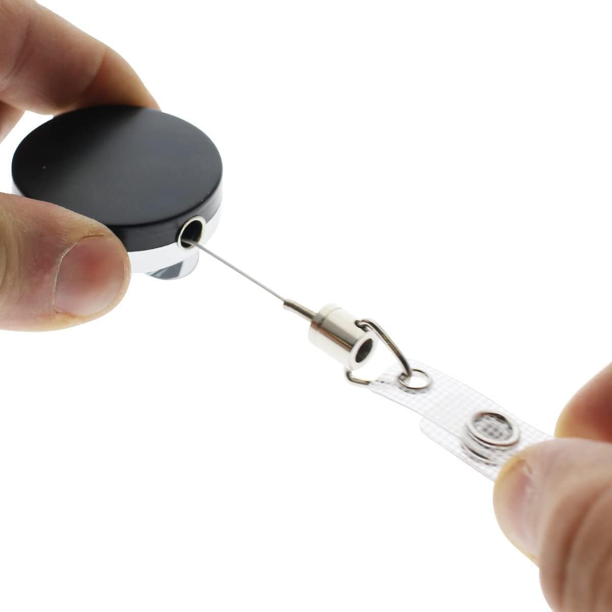 Hands holding a Heavy Duty Badge Reel With Steel Cable 2120-3305 with a black top and a metal cord being pulled out.