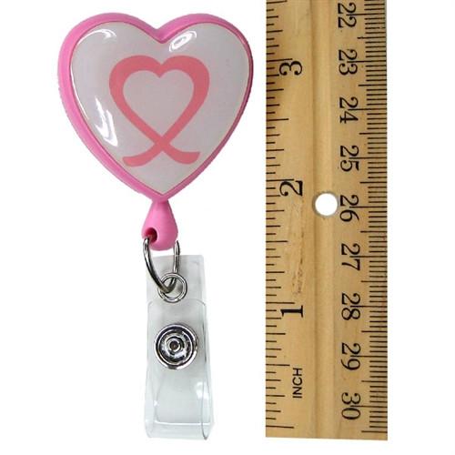 A Heart Shaped Ribbon "Awareness" Badge Reel with Swivel Spring Clip (P/N 2120-7630) hangs next to a ruler showing a height of approximately four inches, featuring a convenient swivel spring clip for easy attachment.