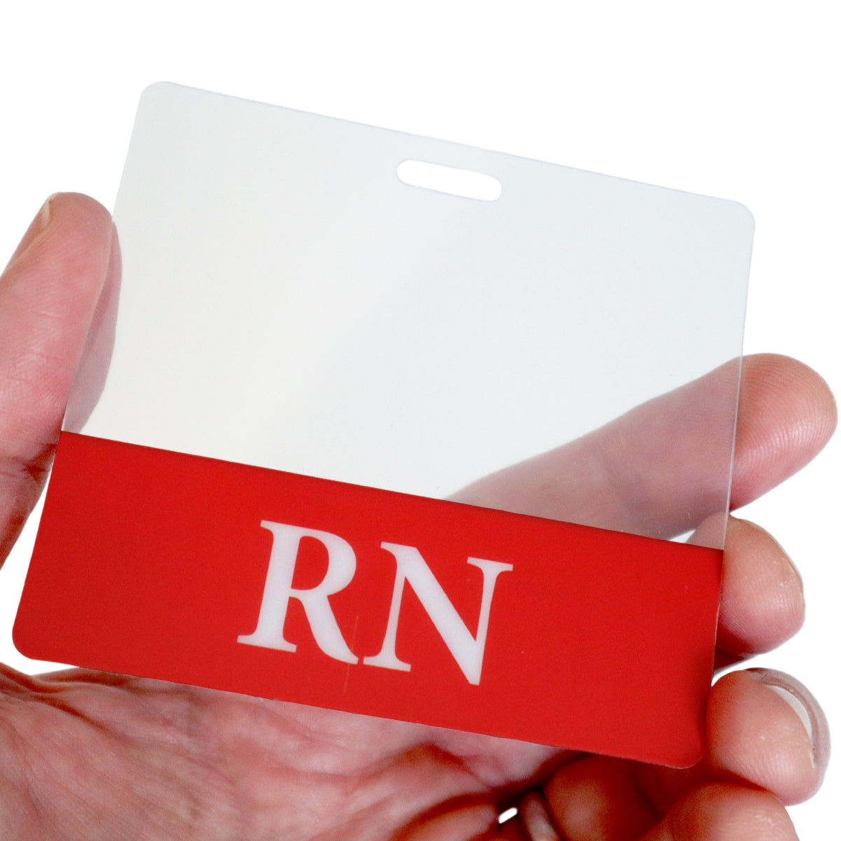 A hand holds a Clear RN Badge Buddy - Horizontal ID Badge Backer for Nurses - Double Sided Print with a red and white design and the letters "RN" clearly displayed on it.
