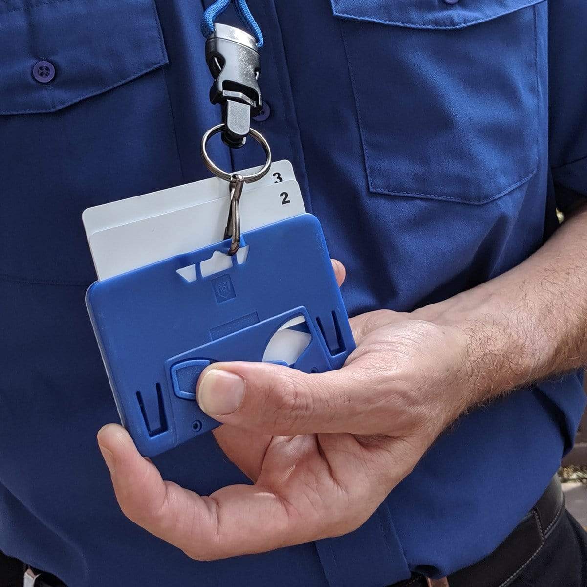 Person in professional work wear featuring a blue shirt, holding a Specialist ID Horizontal 3 Card Badge Holder & Heavy Duty Lanyard with Breakaway Clip and Key Ring - Hard Plastic Rigid Name Tag Protector -Top Load for Three Badges with two cards visible.