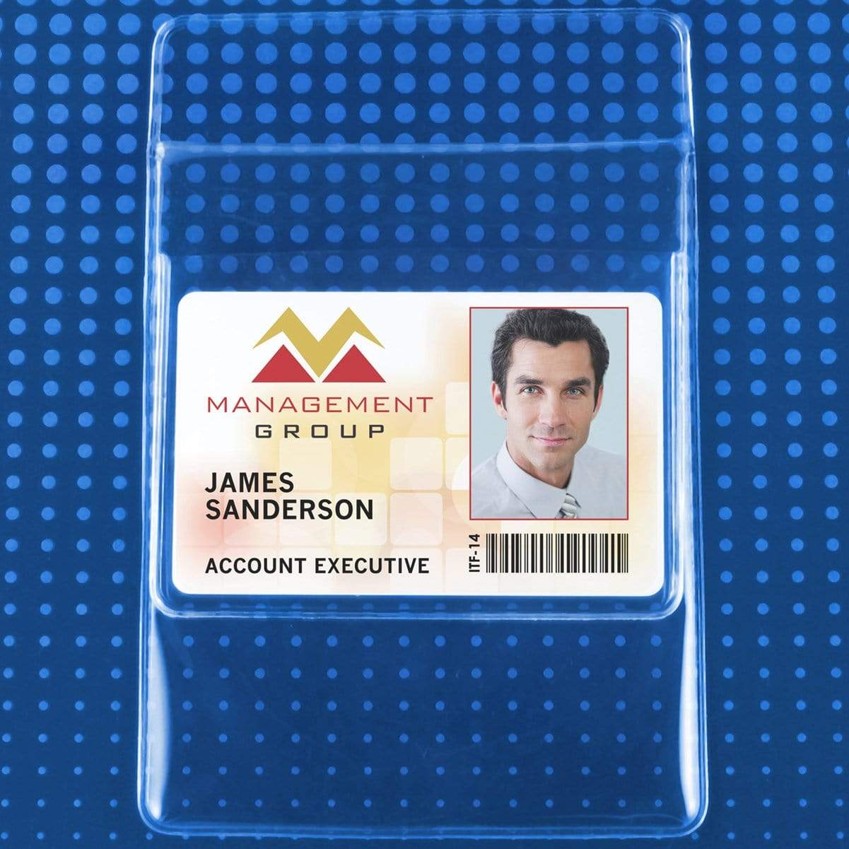 Photo of a Clear Vinyl Pocket Protector With ID Badge Holder (P/N PPL63X) displaying the logo for "Management Group," a photo of a man in a suit, the name James Sanderson, the title Account Executive, and a barcode at the bottom right. The durable vinyl material ensures long-lasting use.